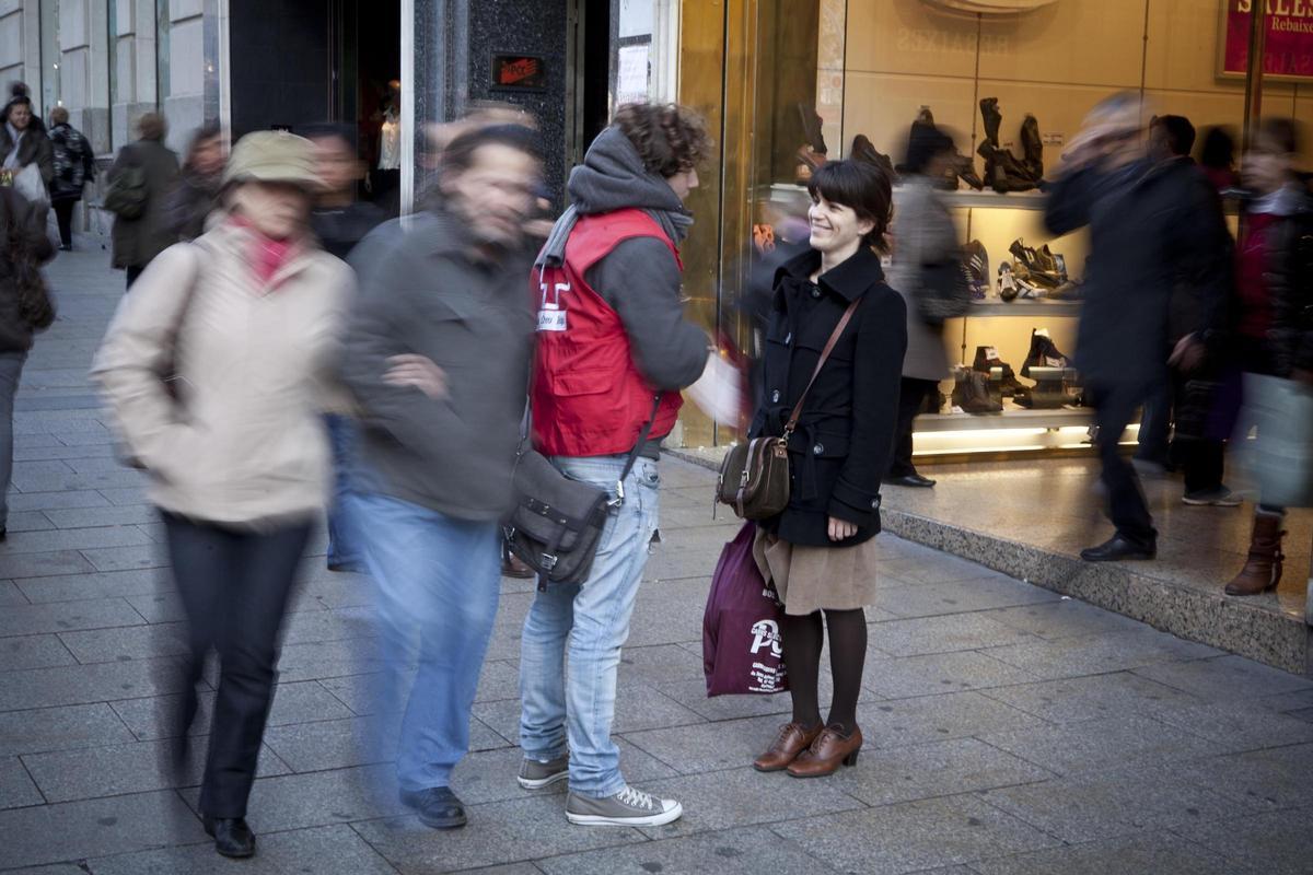 Una persona dona dinero a una oenegé en la calle, con una expresión de duda en su rostro. (Fuente: El Periódico Economía)