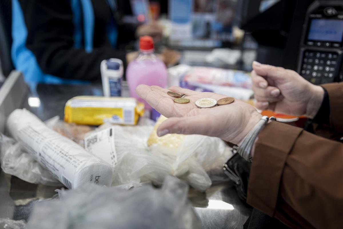 Una mujer repasando su lista de la compra en un supermercado, sonriendo al encontrar una oferta. (Fuente: El Periódico)