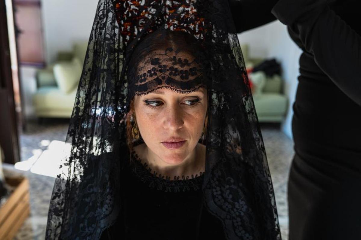 Una mujer ayuda a otra a ponerse la tradicional mantilla este Jueves Santo, en Sevilla. (Fuente: El Periódico)