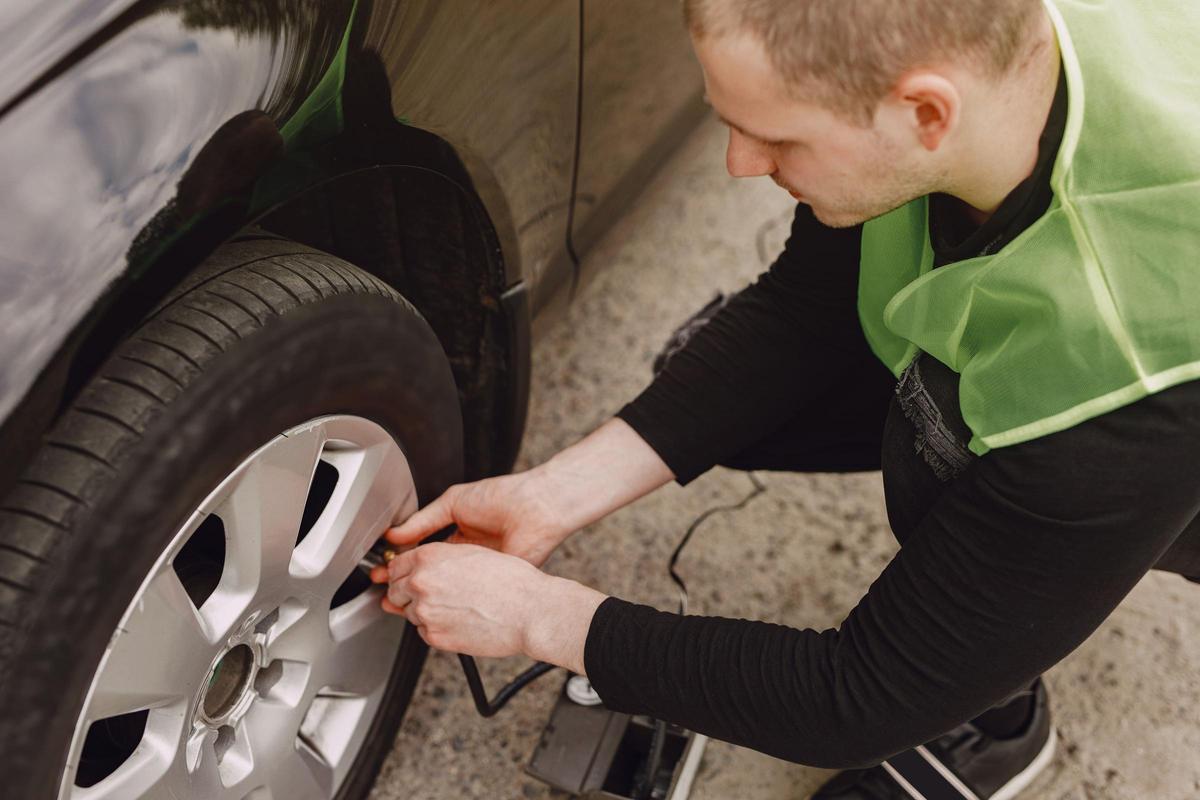 Hombre revisando los neumáticos de su coche para evitar imprevistos en la carretera (Fuente: El Periódico)