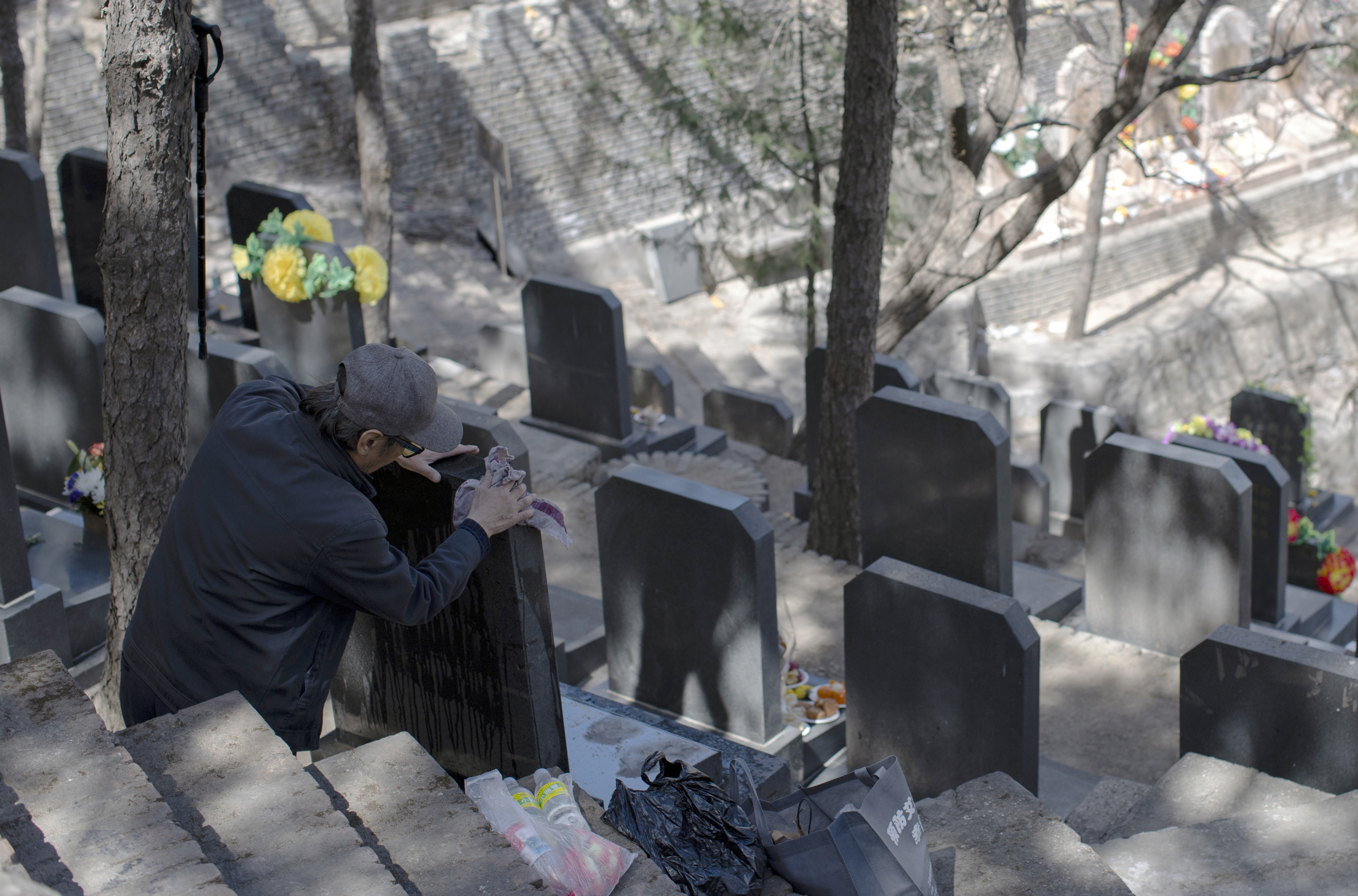 Una mujer china contratada para llorar en un funeral, con una tumba al fondo. (Fuente: El Mundo)