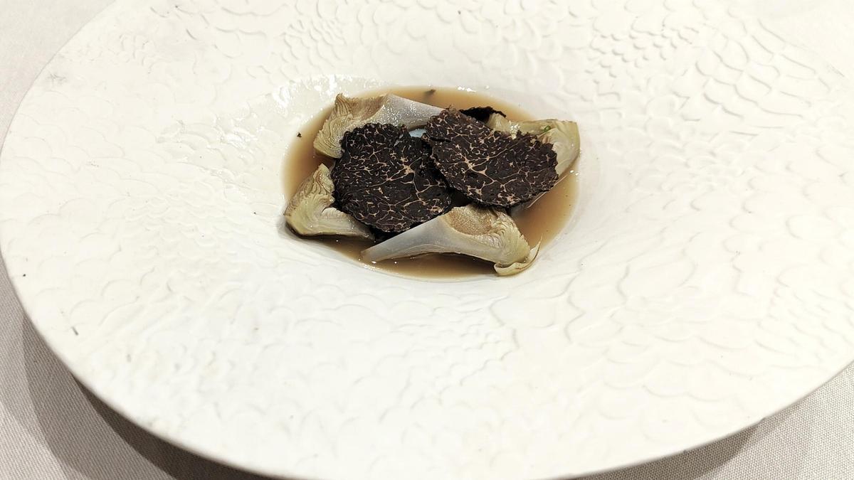 El corazón de alcachofa a la brasa con consomé de jamón de Saroa, un plato que refleja la pasión por la cocina de la pareja de chefs. (Fuente: El Periódico)