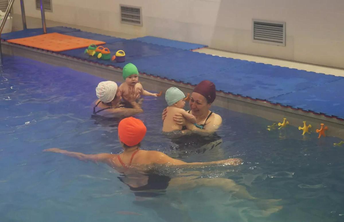 Bebé flotando en brazos de su madre durante una clase de matronatación en el Gimnasio Arenal, Vigo.
