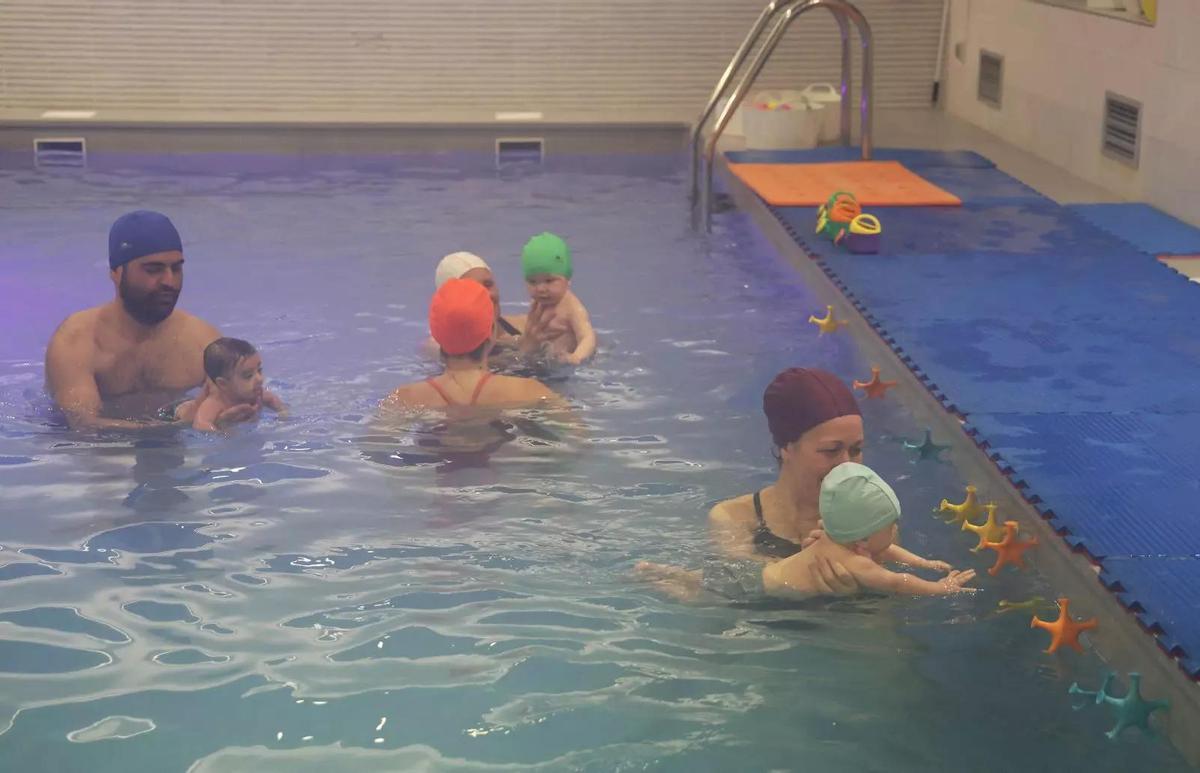 Grupo de bebés y cuidadores en la piscina de Nubes Blancas, mostrando juegos acuáticos.
