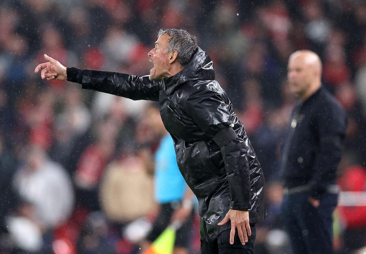 Jugadores del PSG celebran su victoria en Anfield frente a un estadio vacío y luces brillantes.