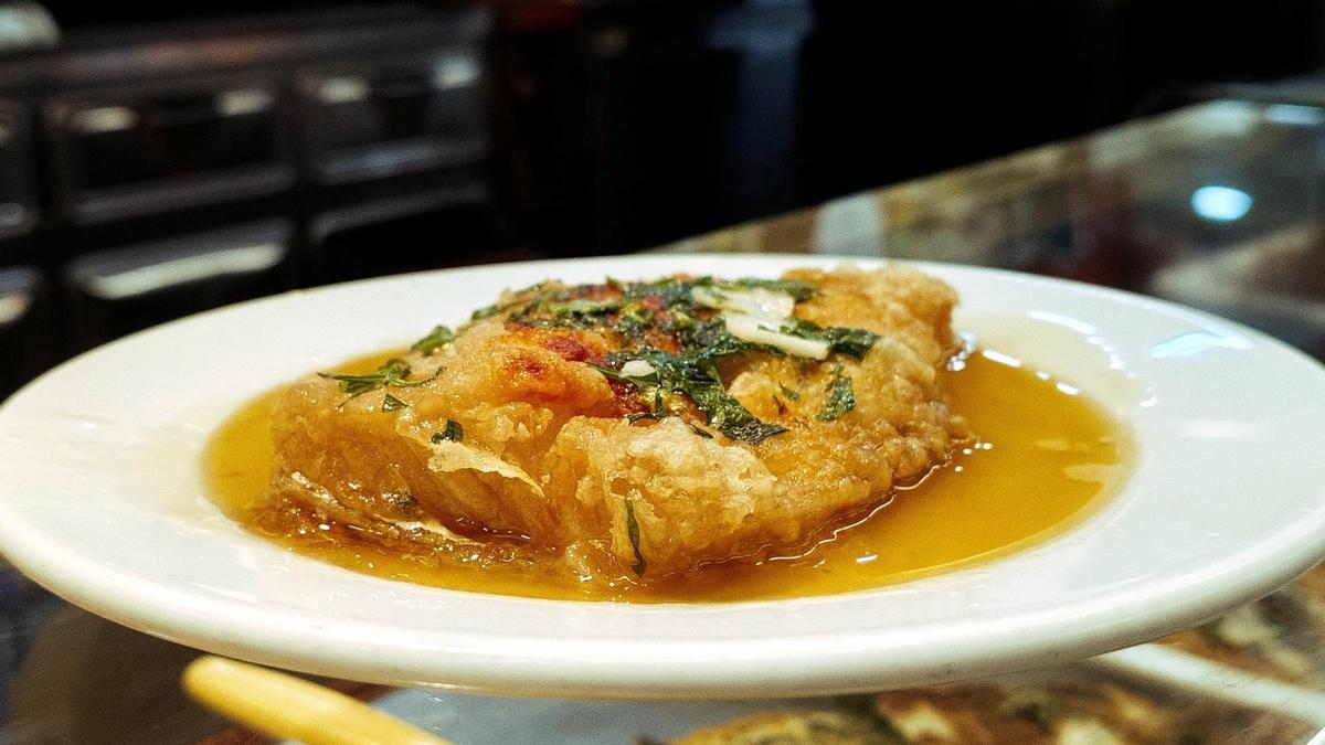 Bar Joan en el mercado de Santa Caterina, mostrando su barra monumental y una porción de bacalao a la llauna