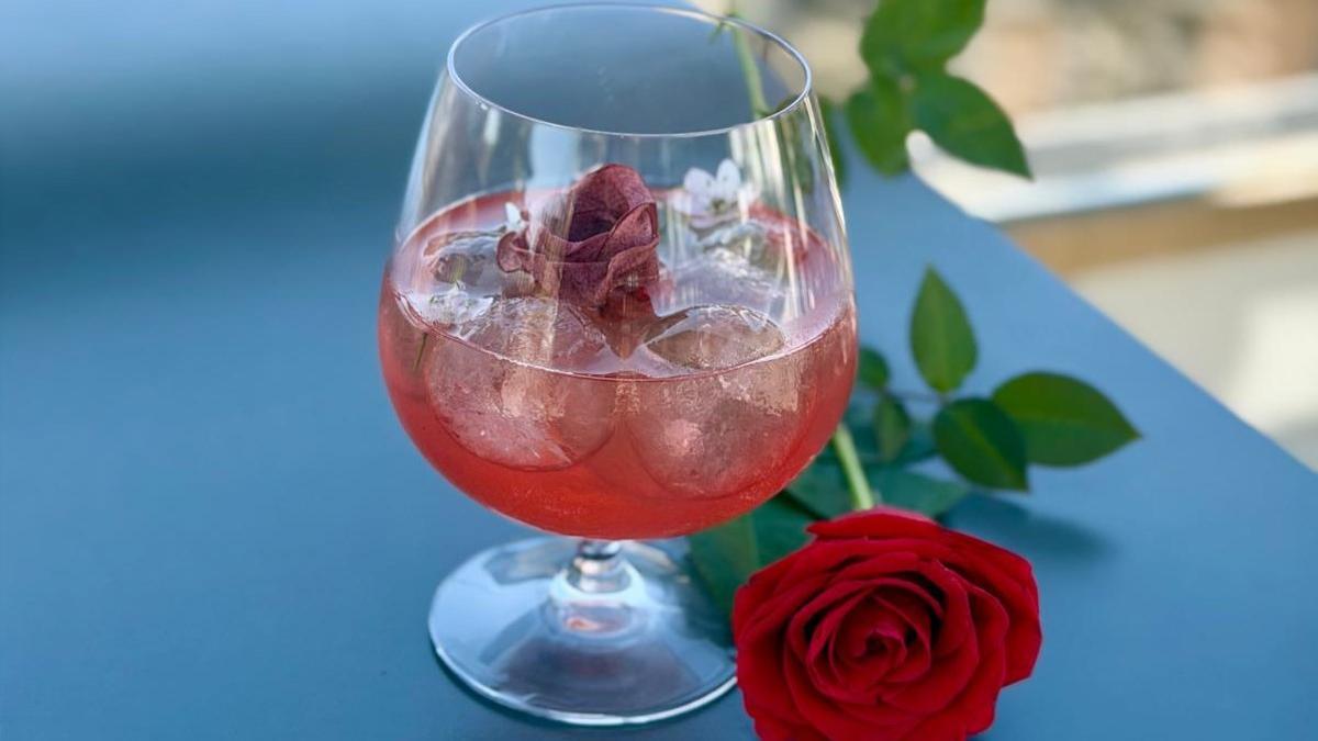Botella de vino La Rosa (Can Sumoi) sobre una mesa decorada con rosas y libros