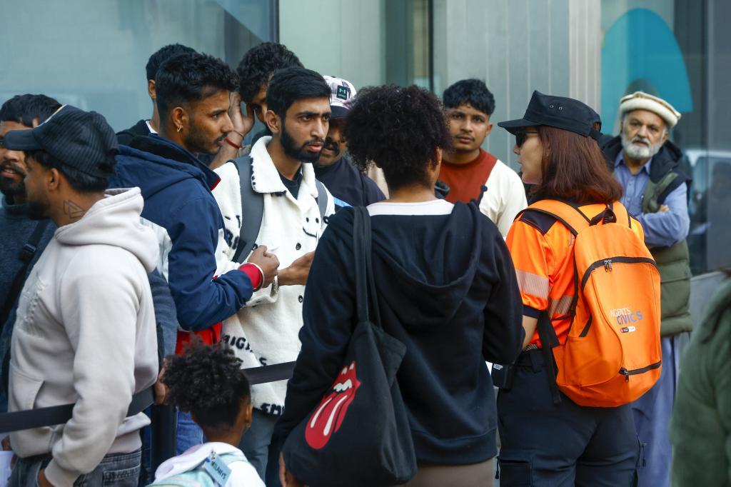 Mujeres migrantes con carpetillas de documentación esperando en la oficina de Correos