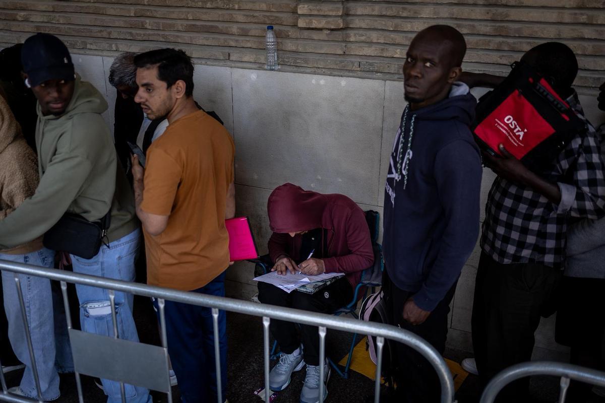 Migrante rellenando el formulario de solicitud en la fila del Ayuntamiento