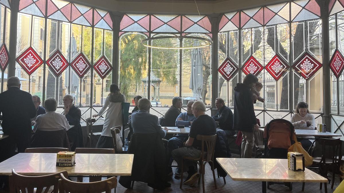 Vista de la terraza de Can Deu con mesas de mármol y zinc bajo la luz ámbar