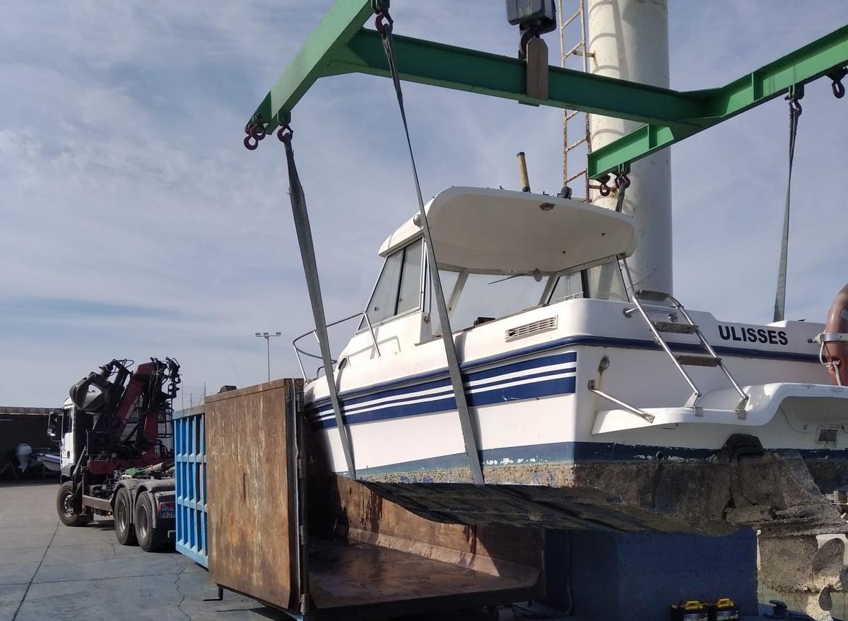 Operarios trasladando una embarcación abandonada para su desguace en la costa de Cataluña
