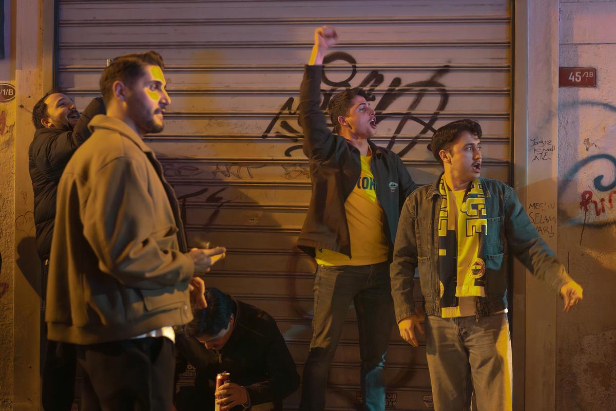 Aficionados de Fenerbahçe bebiendo cerveza y gritando frente a una pantalla gigante en un bar de Kadiköy