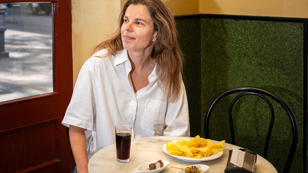 Núria Domènec hablando frente a cámara mientras muestra un plato típico catalán en un restaurante de Barcelona