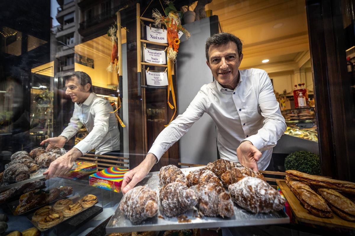 Interior de la Pastisseria Ideal, con vitrinas de dulces y mesas de madera