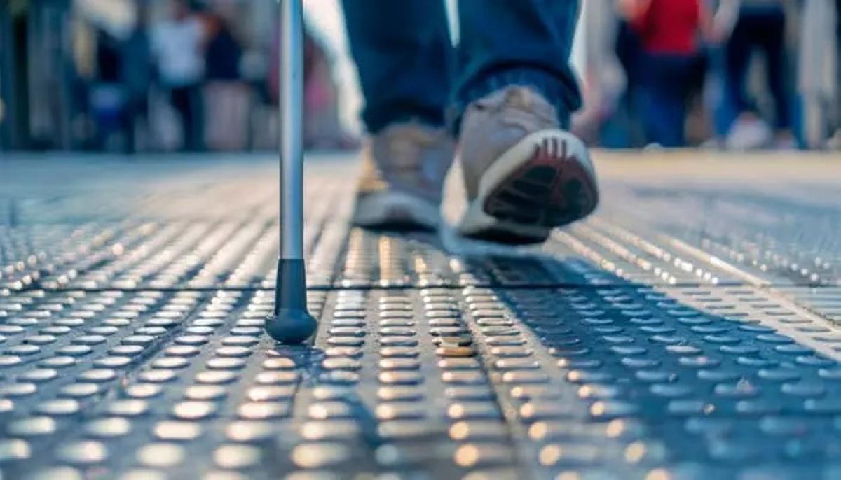Joven ciego Guille Pelegrín usando el bastón y siguiendo la cinta podotáctil en la estación Moncloa del Metro de Madrid