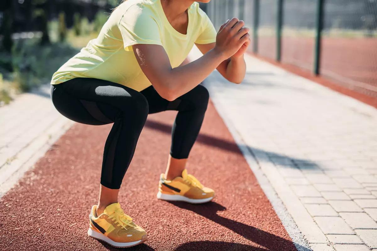Corredor realizando sentadillas con postura incorrecta en el gimnasio