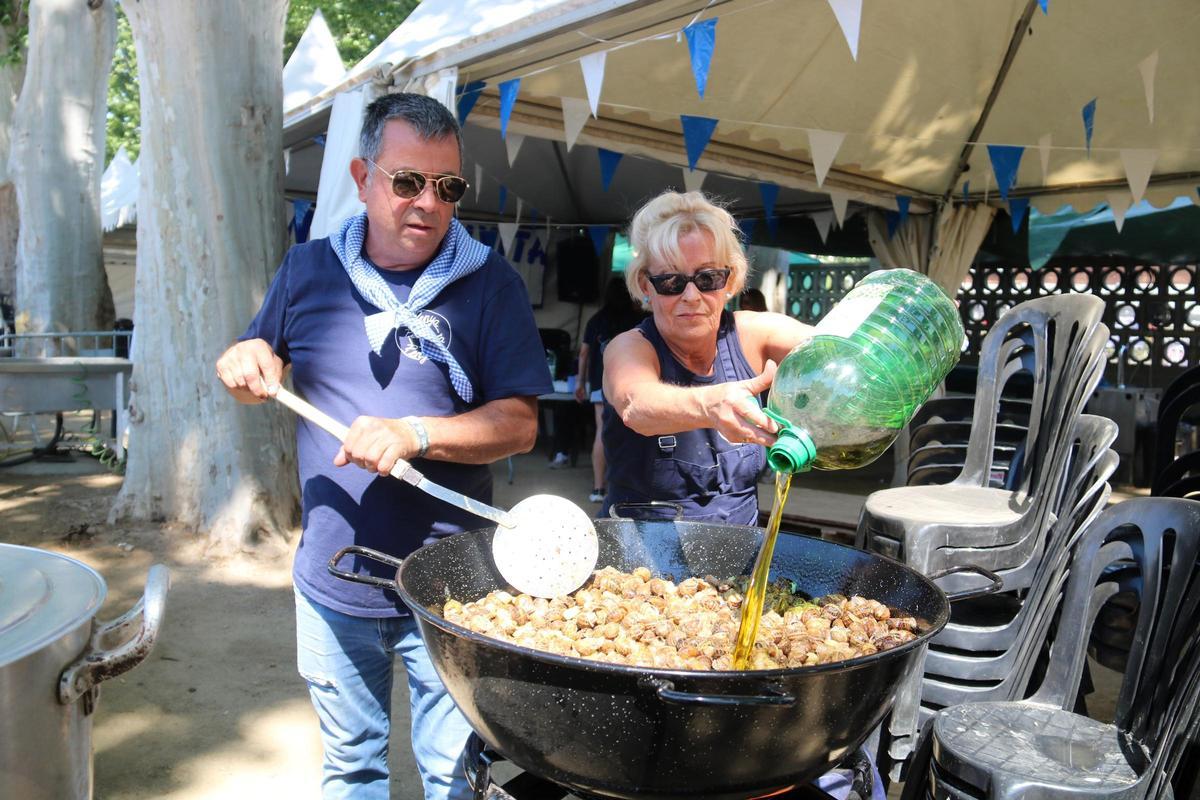 Peñistas cocinando caracoles a la llauna bajo el sol en los Camps Elisis