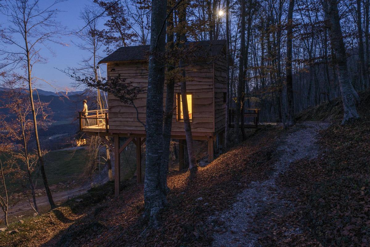 Cabaña de madera al atardecer con el valle de Bianya de fondo