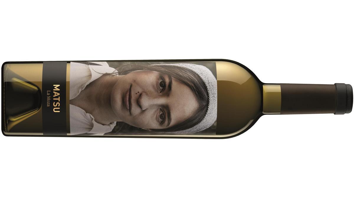 Botellas de los cuatro vinos blancos económicos alineadas sobre una mesa de madera