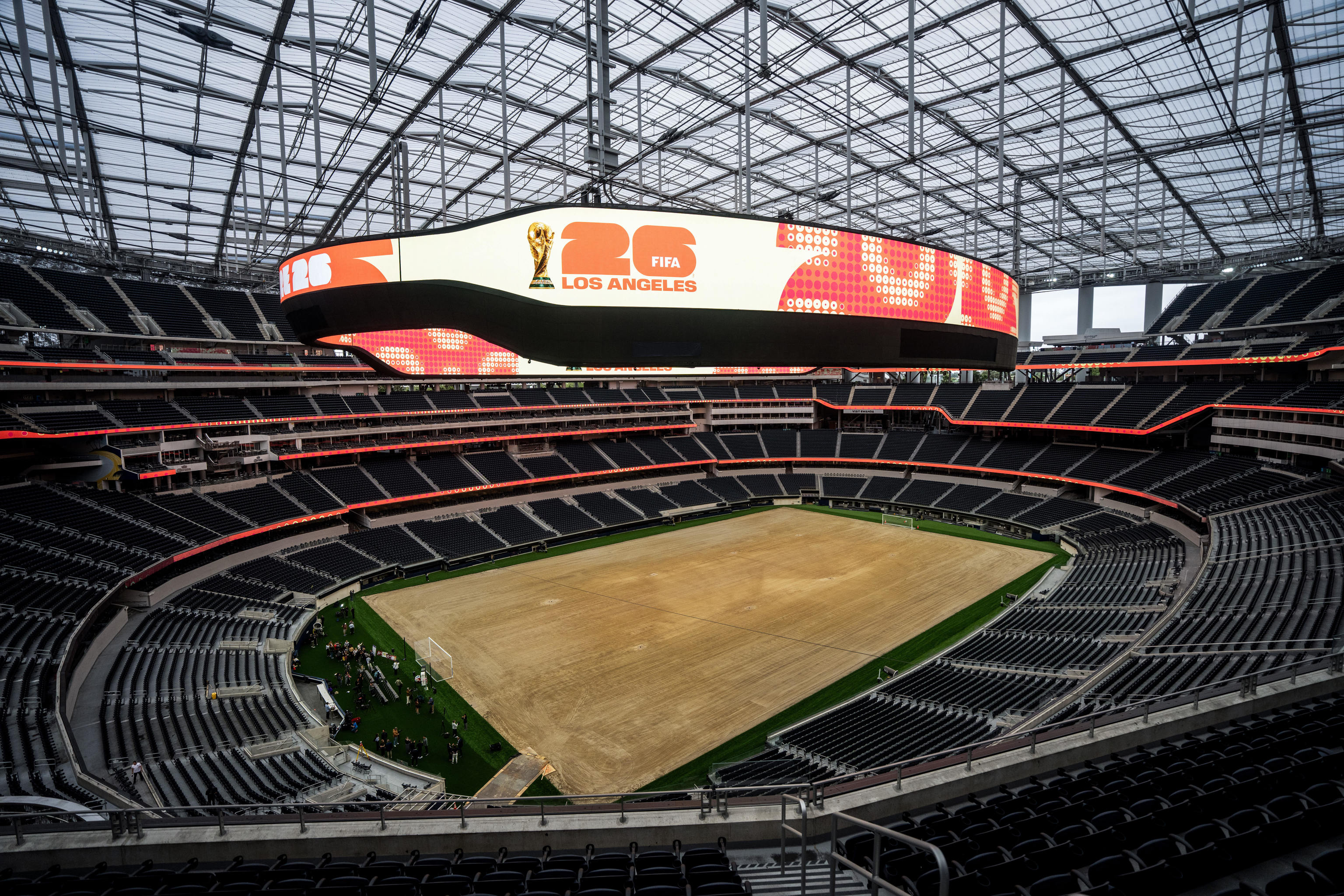 Aficionados latinos mirando una pantalla gigante de fútbol en Los Ángeles, con expresión de desinterés